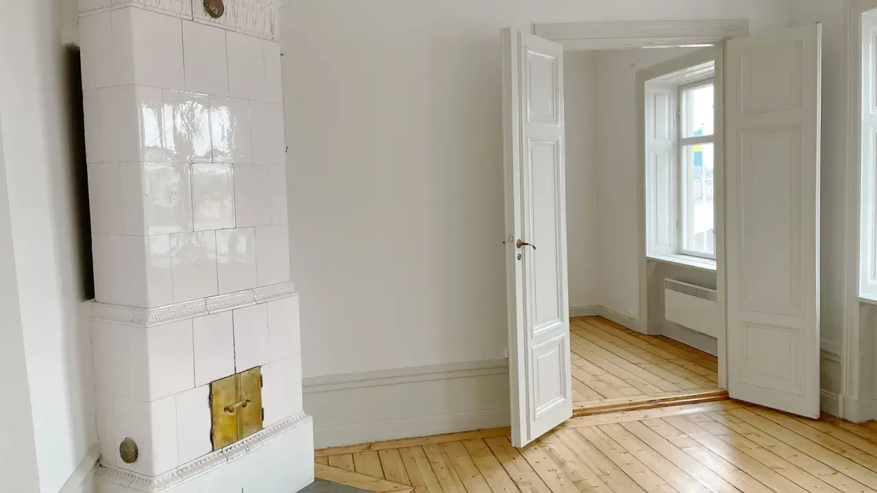 Vitt, vackert kakelugn med mässingsluckor. Tänk att elda i kakelugn en kall vinterdag.