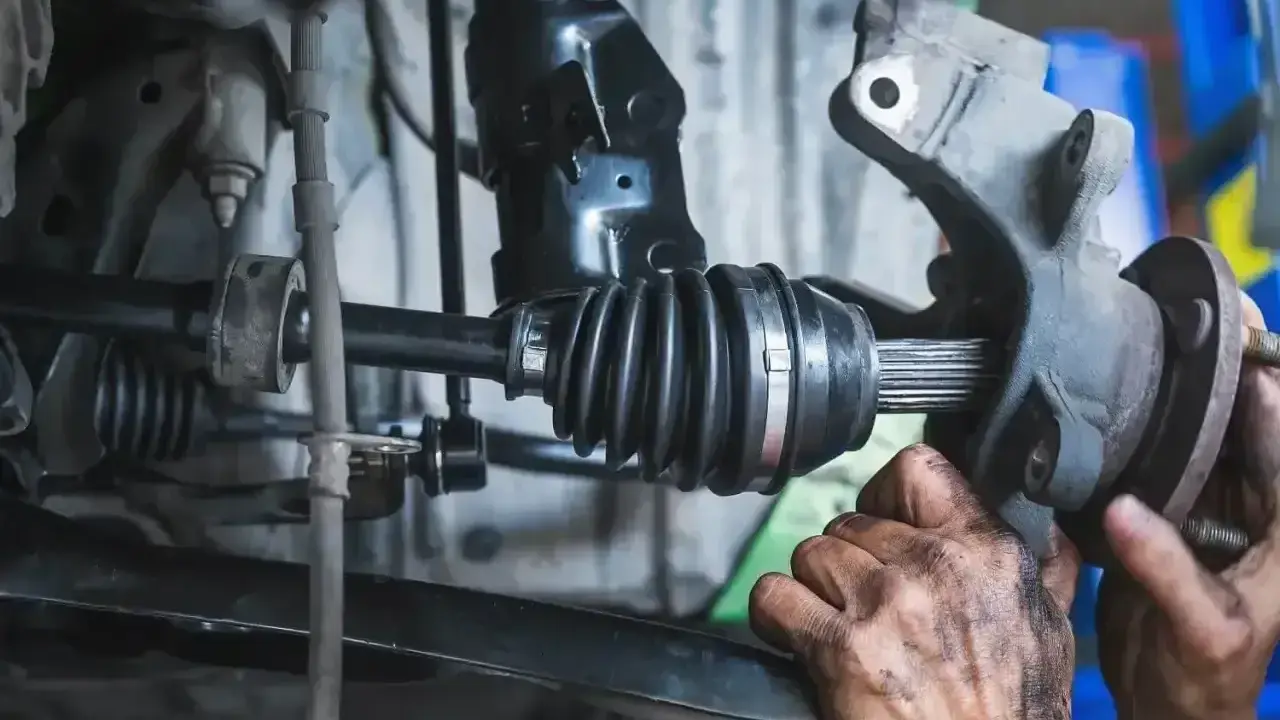 Mechanik sprawdza przegub wewnętrzny, którego uszkodzenie objawia się stukaniem podczas jazdy.