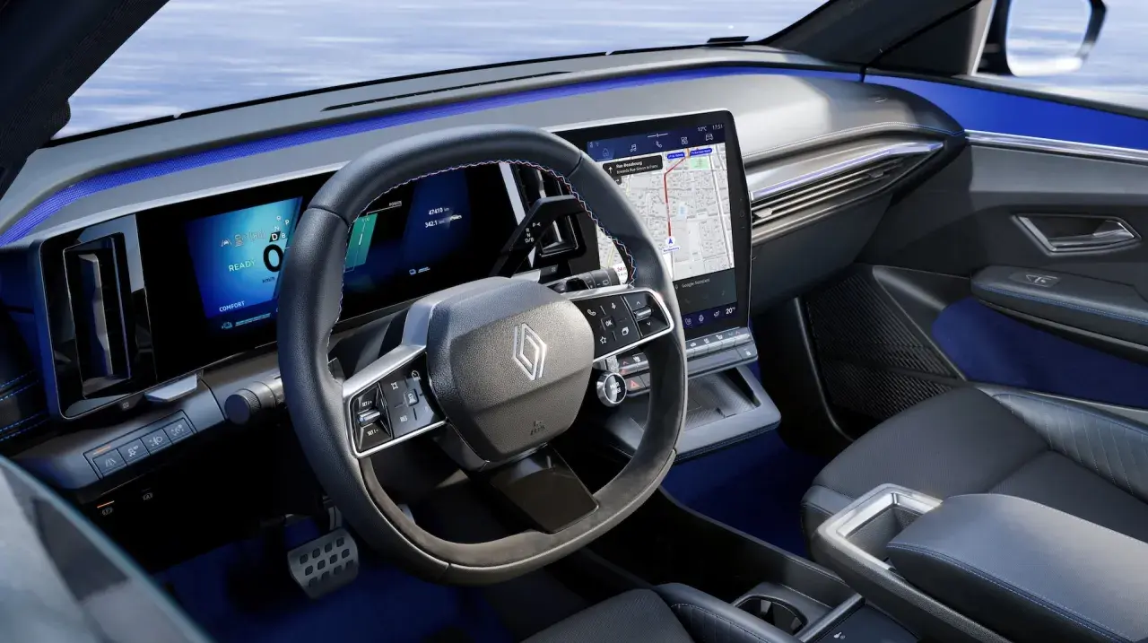 Tableau de bord moderne de la future Renault Mégane, avec écrans numériques, volant multifonction et éclairage d'ambiance bleu.