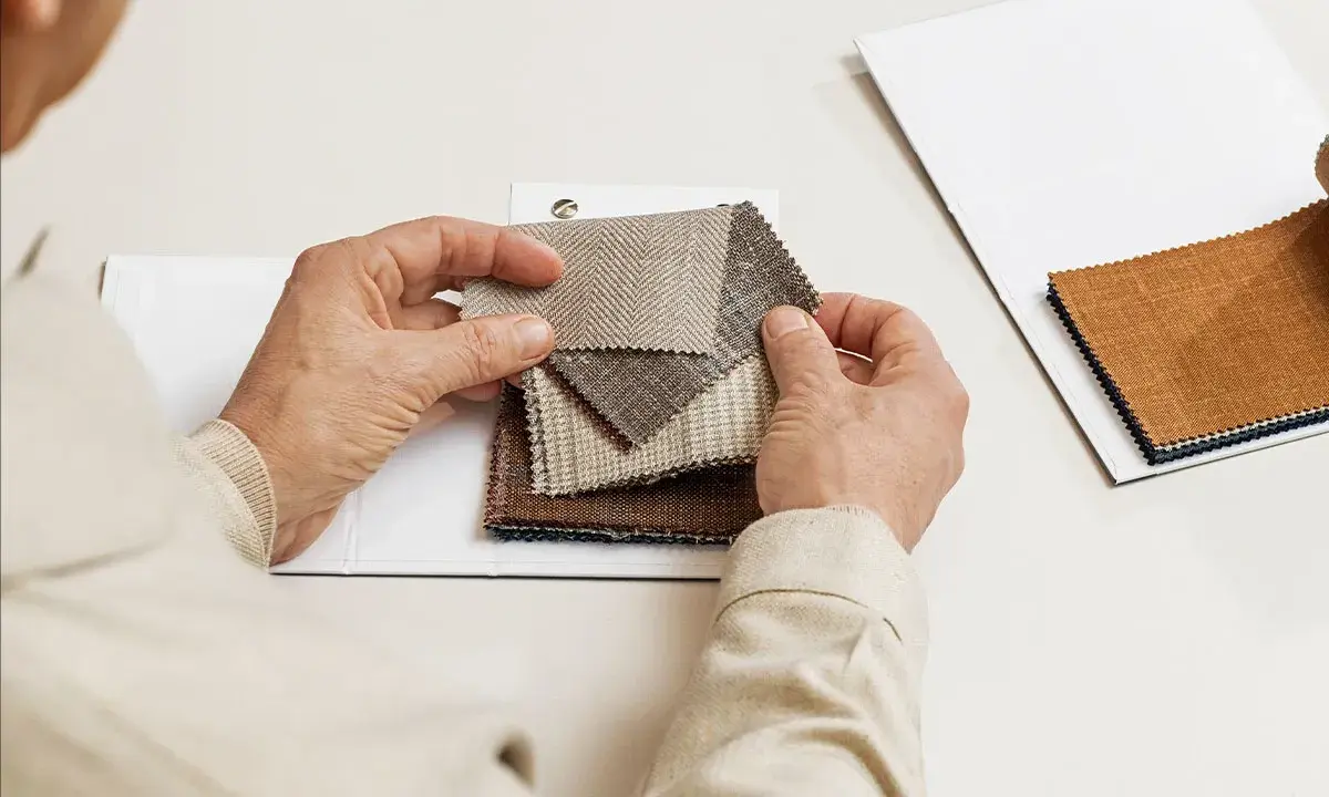 Hands examine fabric swatches, selecting the perfect butterfly lining for a project.