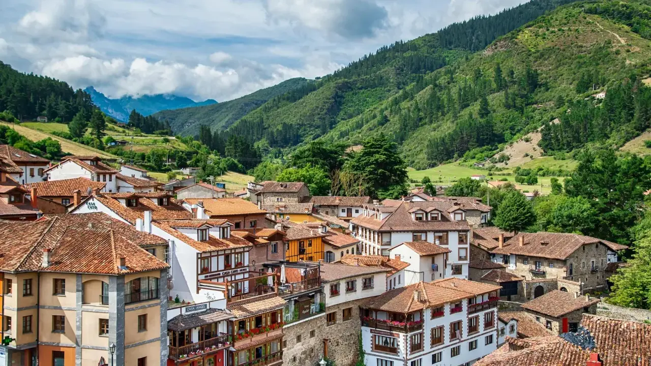 Potes, un pintoresco pueblo en los Picos de Europa, con casas de tejados rojos y montañas verdes de fondo.