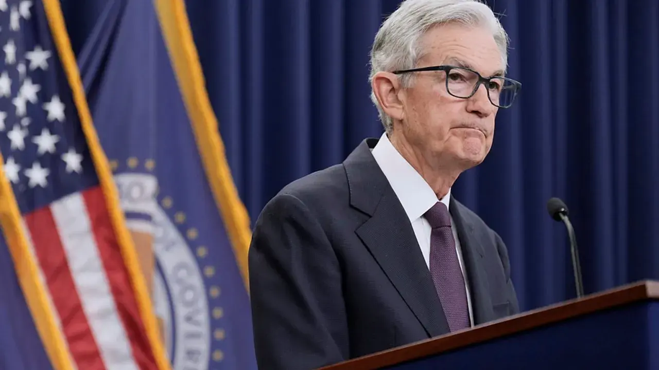 Jerome Powell przemawia na tle flag USA i Rezerwy Federalnej, instytucji, która budzi pytania, czy fed jest prywatny.