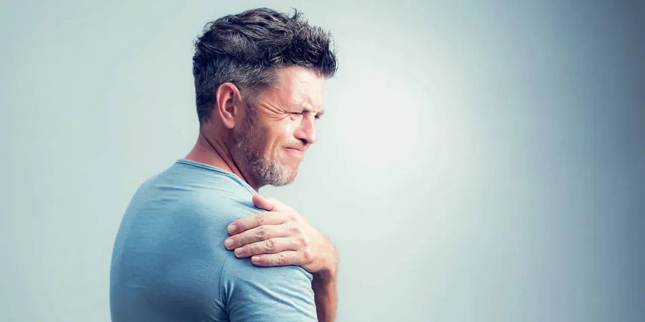 Homme souffrant de douleurs articulaires à l'épaule, possiblement liées à une carence en vitamine B12.