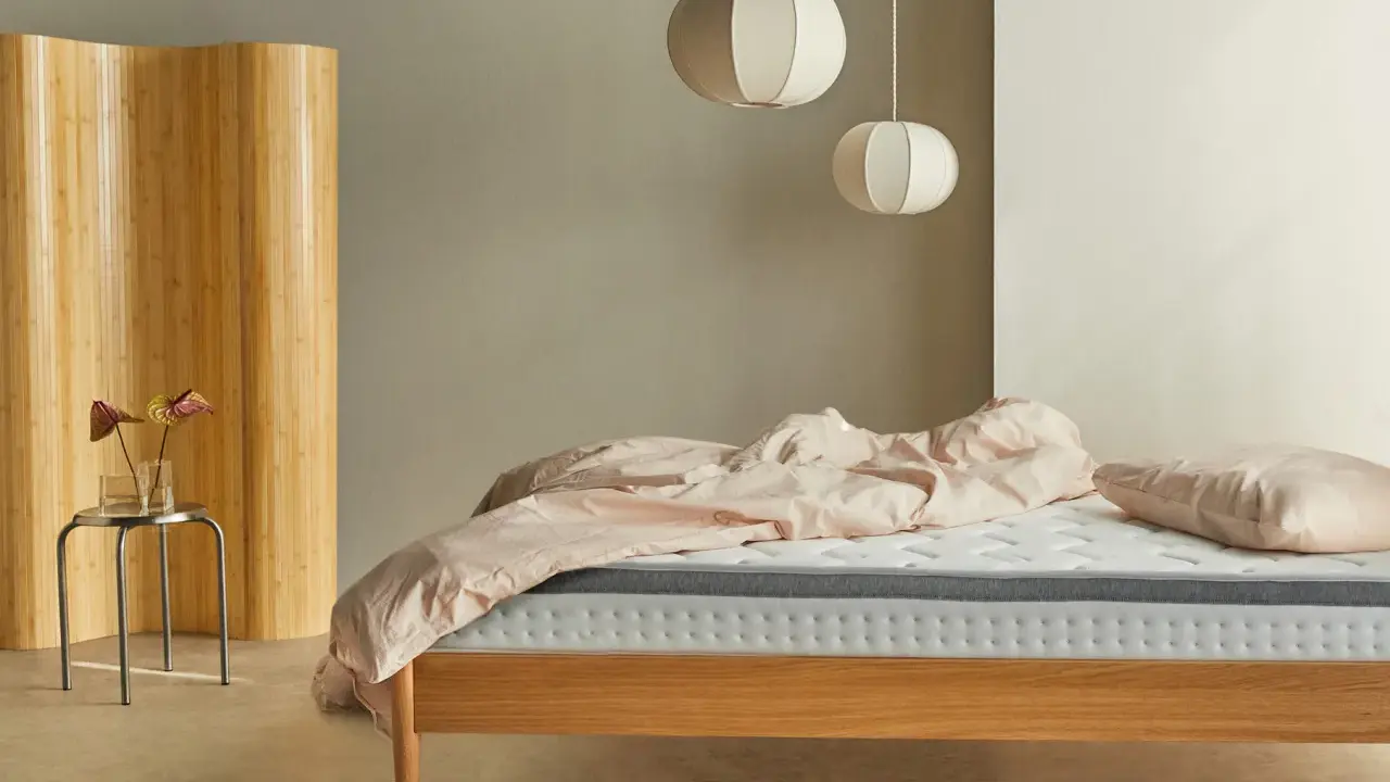 Una habitación nórdica con cama de madera, ropa de cama rosa y un biombo de bambú.