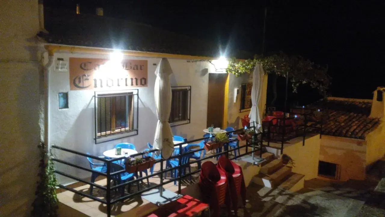 Bar Endrino, un lugar acogedor donde comer en Segura de la Sierra. Mesas y sillas azules y rojas esperan bajo luces cálidas.