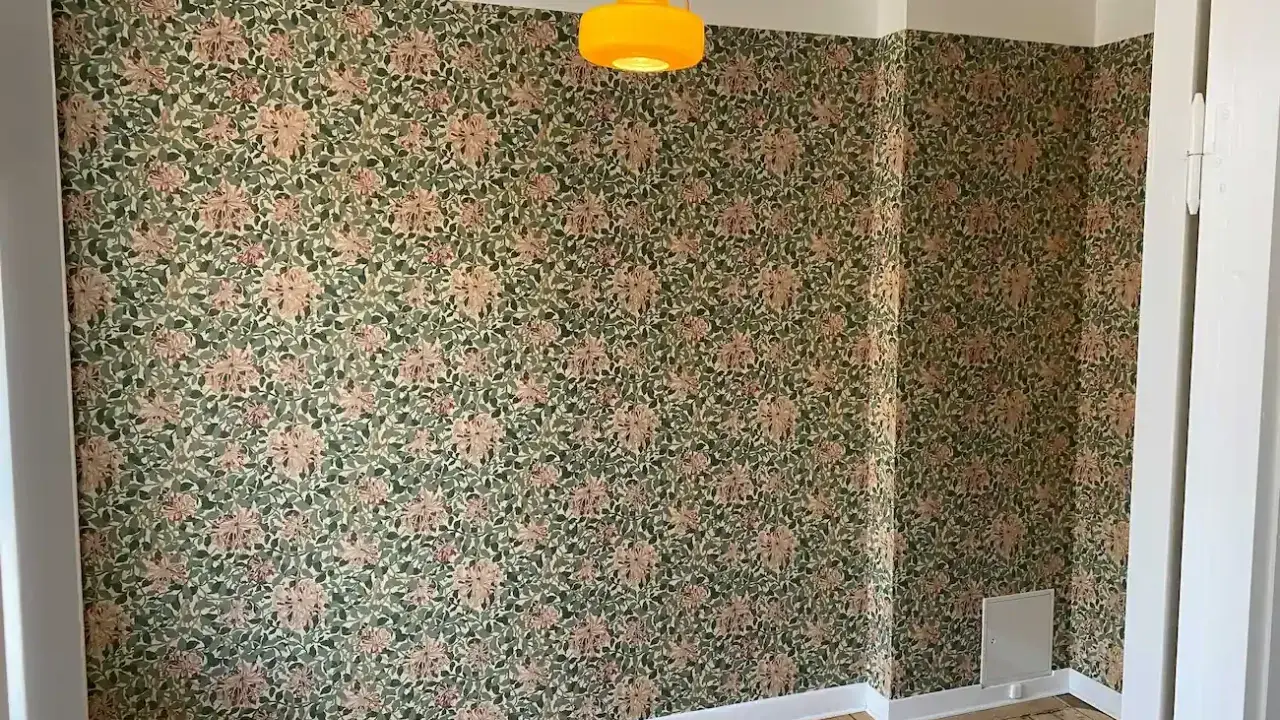 Ett rum med blommig tapet och en gul lampa. Undrar vad kostar det att måla om ett rum?
