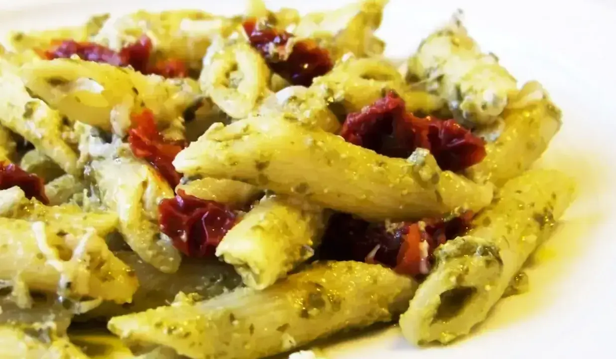 Penne z pesto i kawałkami suszonych pomidorów, posypane parmezanem. Pyszne danie, które zachwyci każdego miłośnika makaronu z suszonymi pomidorami.