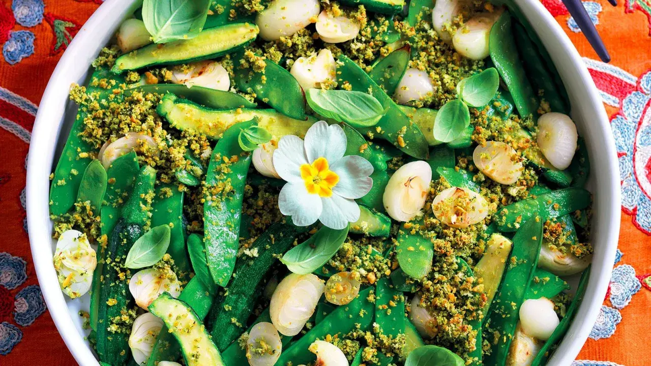 Un colorato contorno di verdure miste, con piselli, zucchine e cipolline, condito con pangrattato croccante. Un pranzo della domenica fatto in casa da Benedetta, con un fiore decorativo.