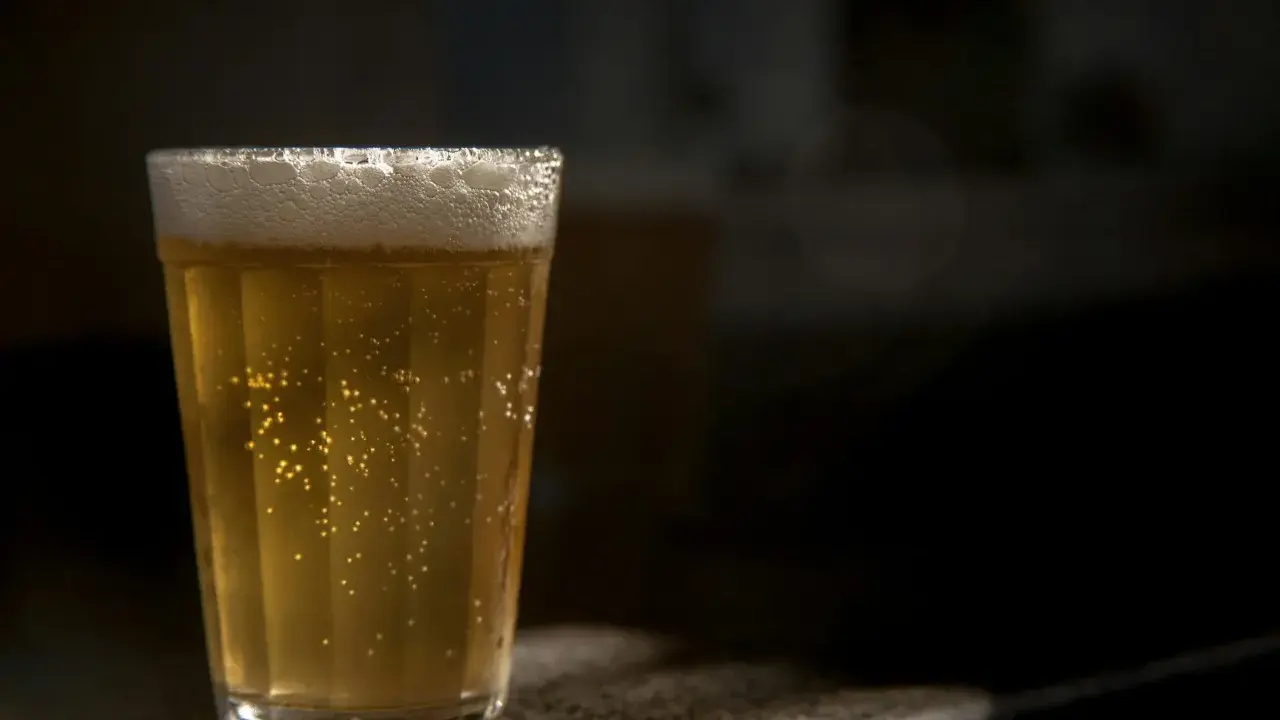 Szklanka złocistego piwa bezalkoholowego, z obfitą pianką i bąbelkami, idealna dla alkoholika szukającego alternatywy.
