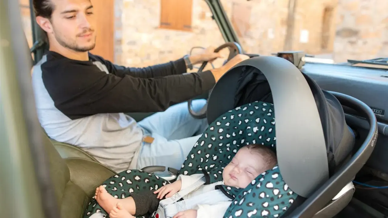 Padre atento conduce mientras su bebé duerme plácidamente en su silla de auto, listo para viajar con bebes.