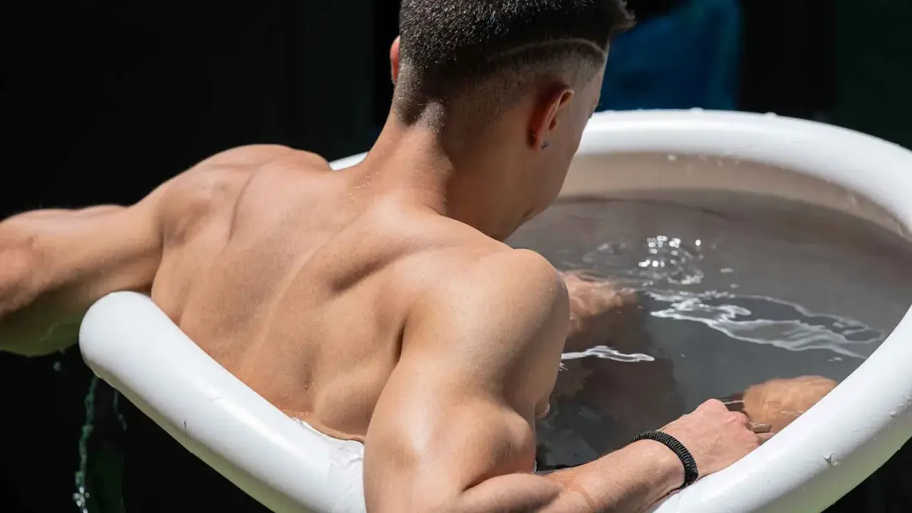 Mann sitzt im Eisbad, bereit für das warme Duschen danach.