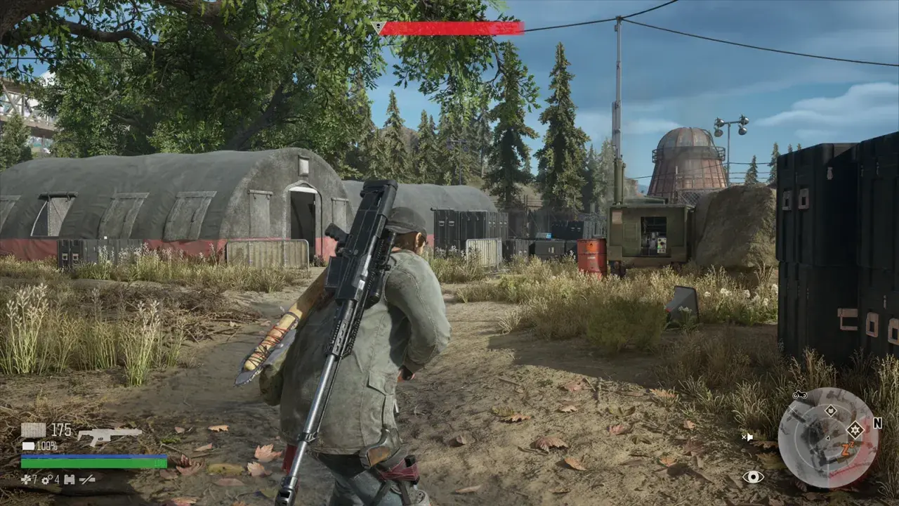 Gracz w Days Gone Remastered z karabinem na plecach przemierza obóz z namiotami i kontenerami.