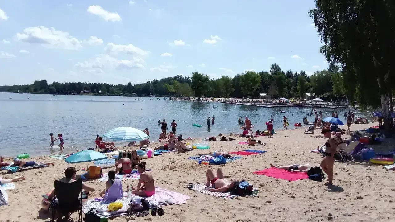 Słoneczny dzień nad zalewem Sosina. Ludzie odpoczywają na plaży, kąpią się i opalają.