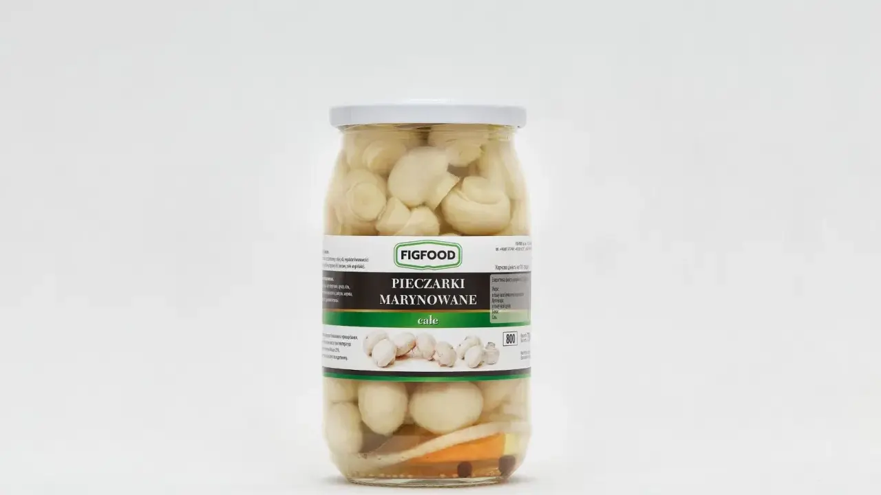 Słoik z marynowanymi pieczarkami marki Figfood, z widocznymi kawałkami warzyw na dnie.