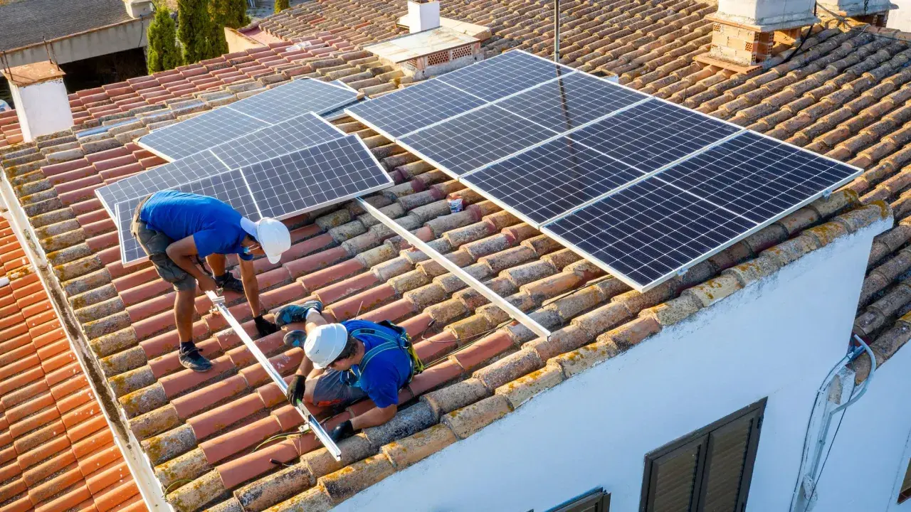 Dos técnicos instalan placas solares en un tejado. Aprendiendo como instalar placas solares para un futuro energético.