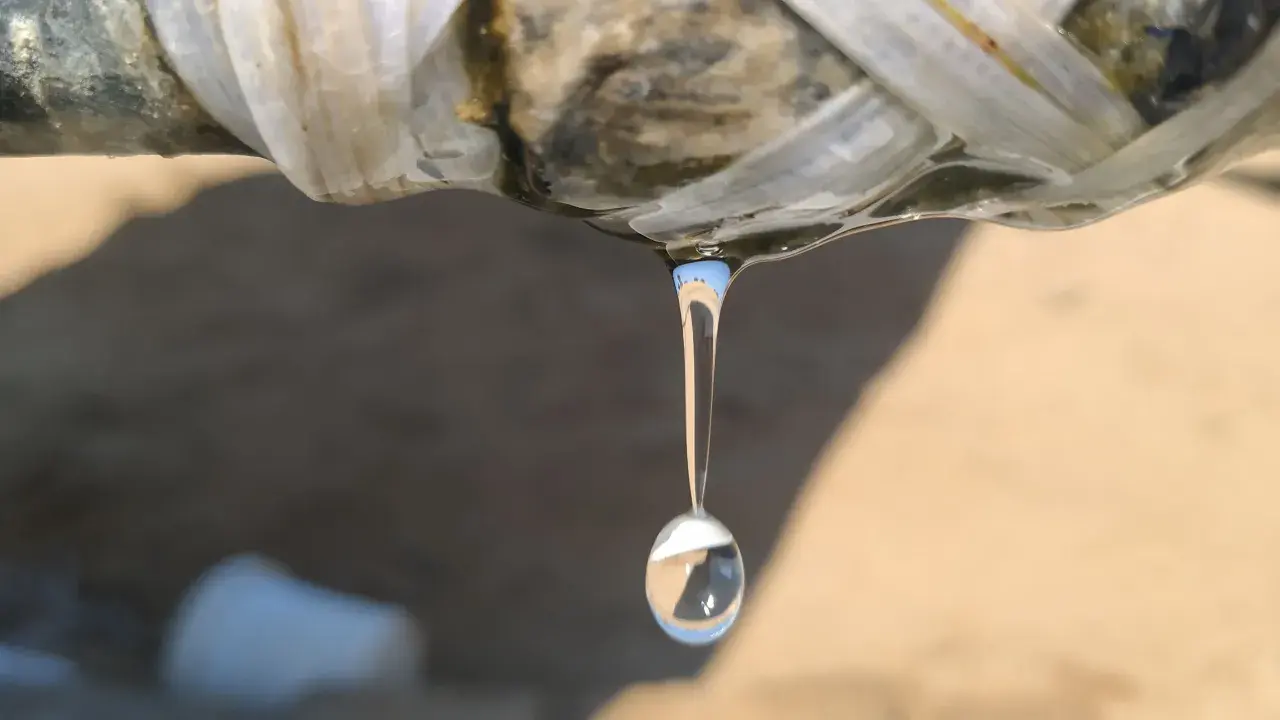Gota de agua cayendo de una tubería rota, indicando la necesidad de reparar tubería.