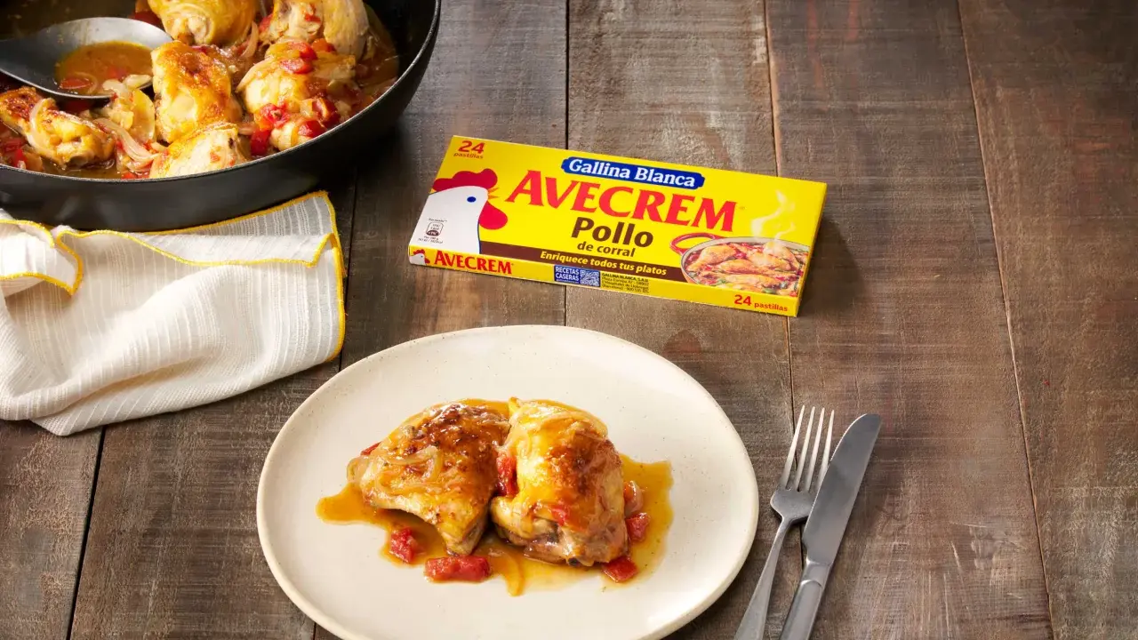 Sabroso pollo con sopa de cebolla y cerveza, servido en sartén y plato. Caja de Avecrem Pollo al lado.
