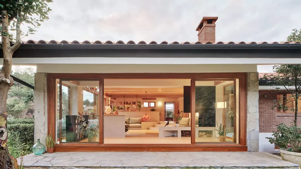 Ristrutturazione esterna di una casa anni '70: un'oasi moderna con ampie vetrate che si aprono sul verde.