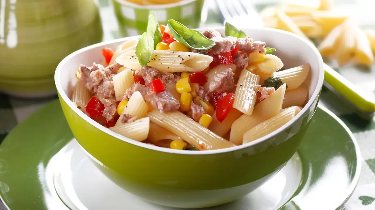 Ein leckerer nudelsalat mit thunfisch, Mais und Paprika, garniert mit Basilikum.