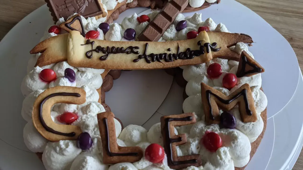Gâteau d'anniversaire en forme de chiffres, décoré de crème fouettée, de biscuits lettres formant "CLEM", de chocolats et de bonbons. Quelle crème pour recouvrir un gâteau ? Celle-ci est parfaite !