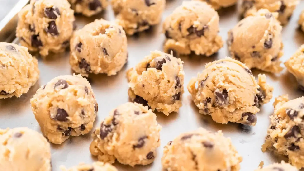 Boules de pâte à cookie au chocolat sur une plaque. Combien de temps la pâte à cookie au frigo se conserve-t-elle ?