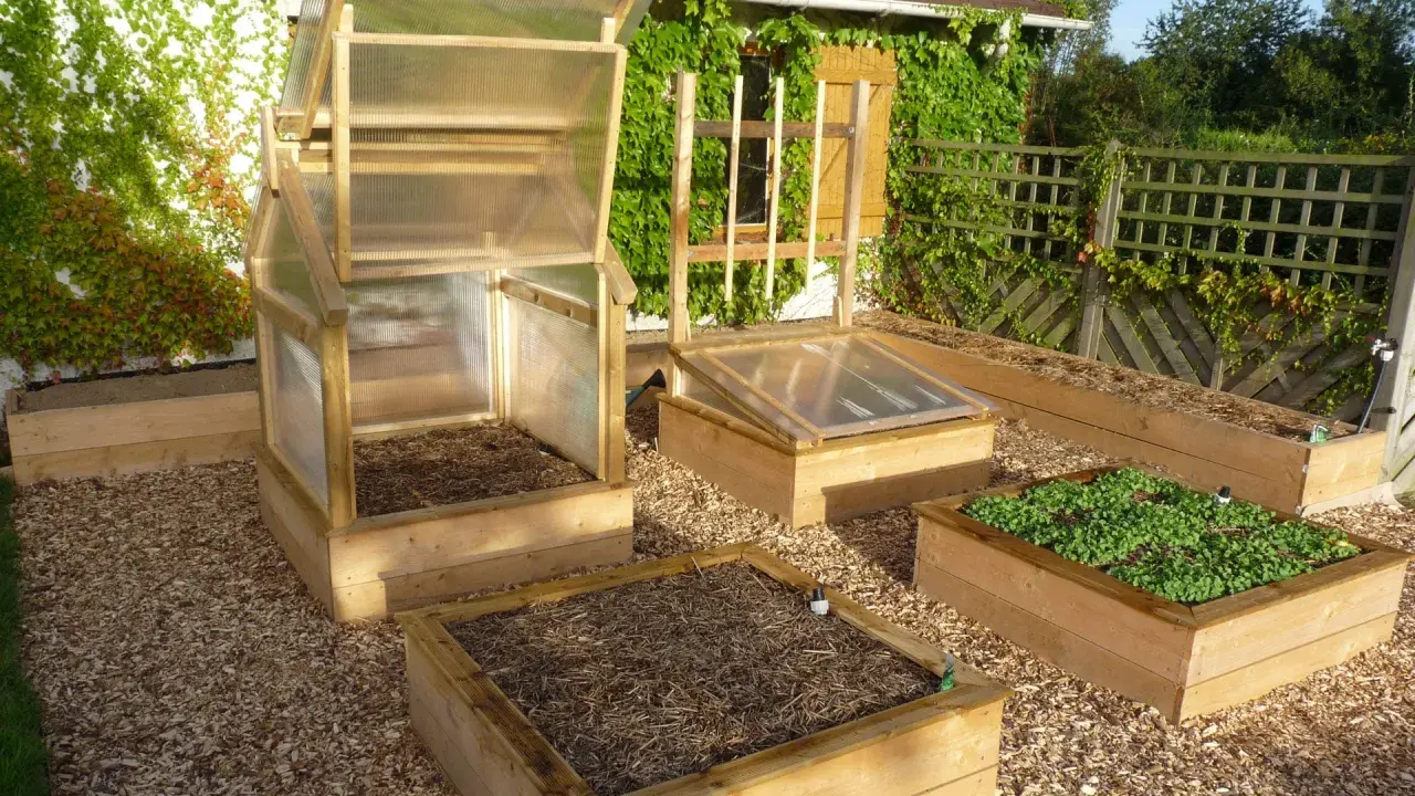 Plusieurs carrés potagers en bois, certains avec des mini-serres, prêts à fabriquer un jardin productif.