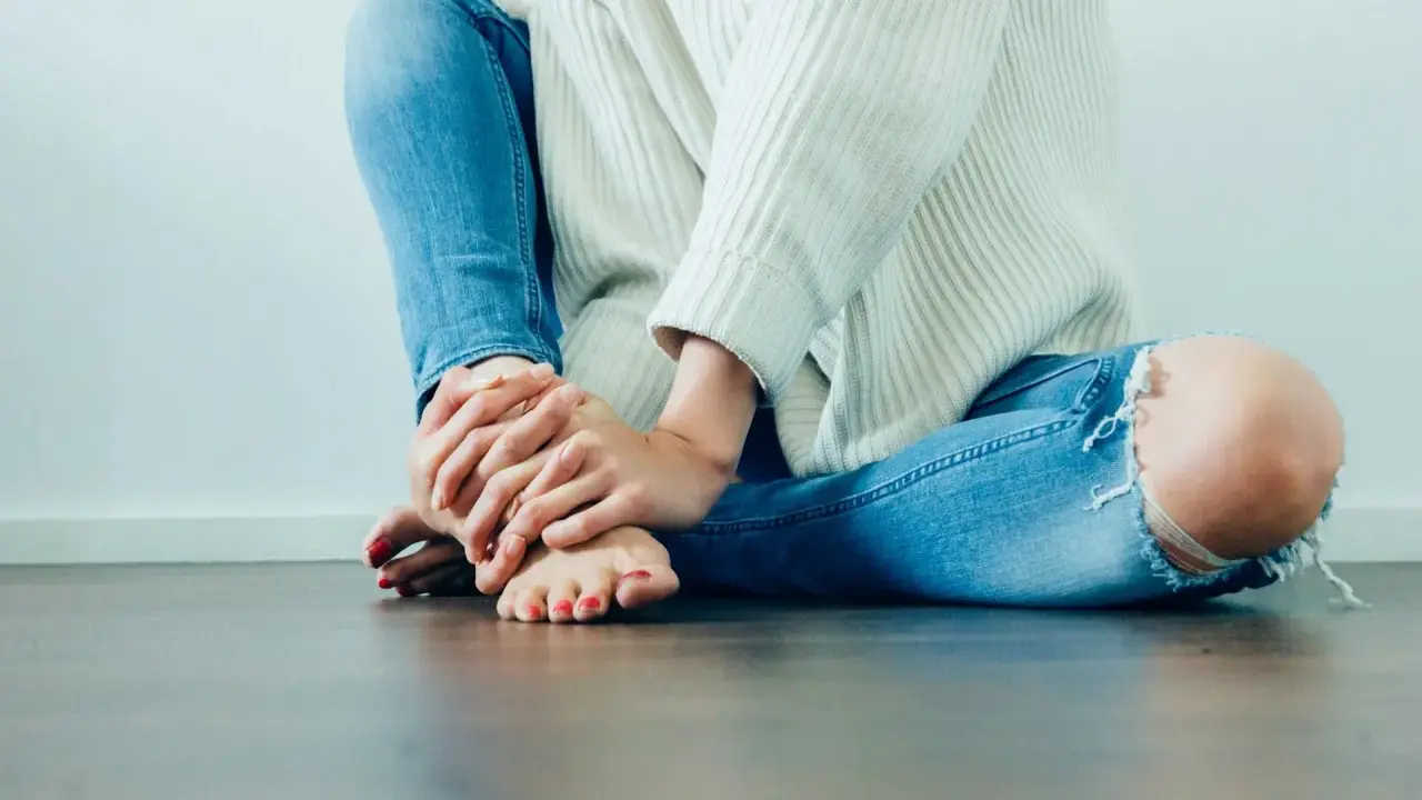 Frau mit zerrissener Jeans hält ihr Bein, das auf Schmerzen Knie Innenseite ohne Schwellung hindeutet.