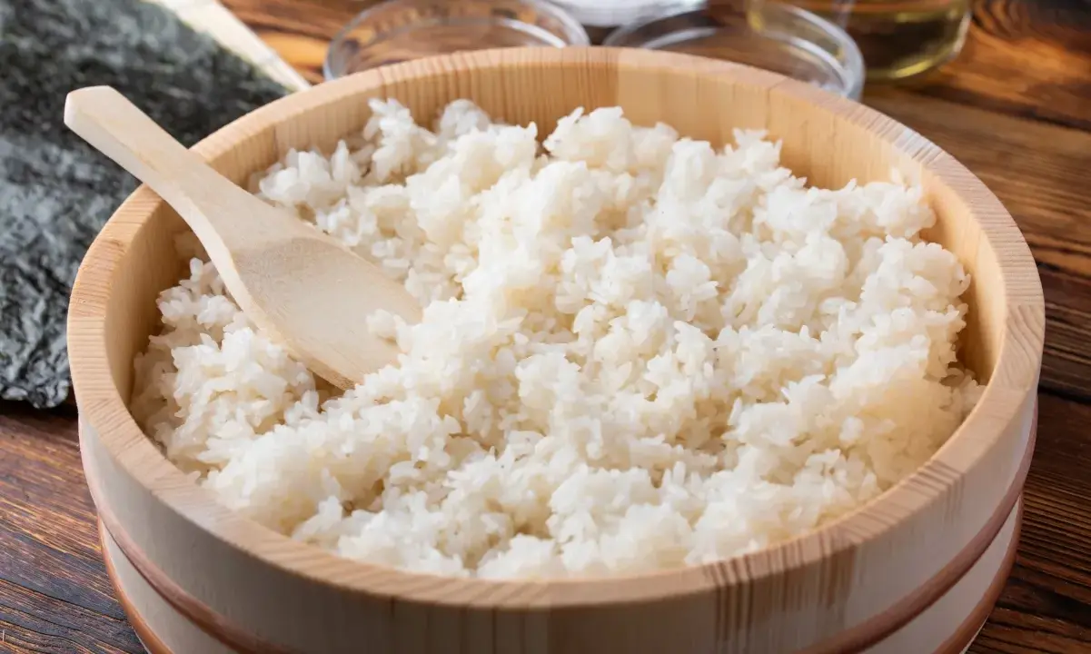 Gotowany ryż do sushi w drewnianej misce z drewnianą łyżką.