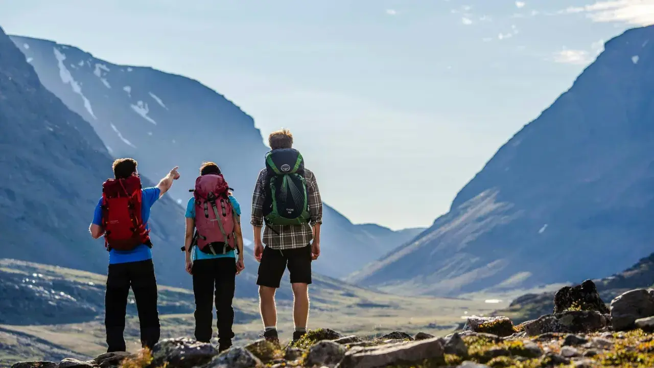Vandrare med ryggsäckar njuter av den storslagna utsikten över fjällen under en abisko sommar.