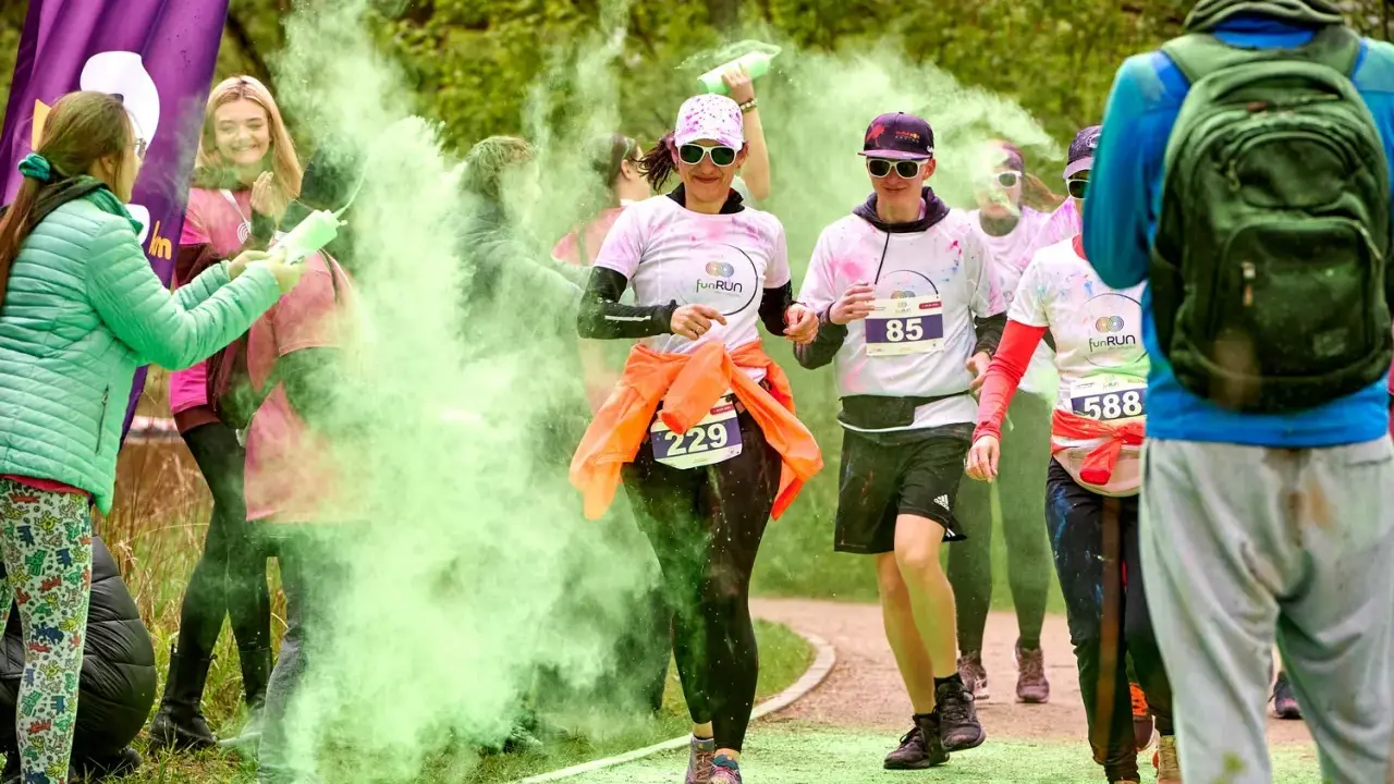 Uczestnicy biegu w kolorowym proszku, w tym 3 forma run, biegną wśród zielonej chmury.