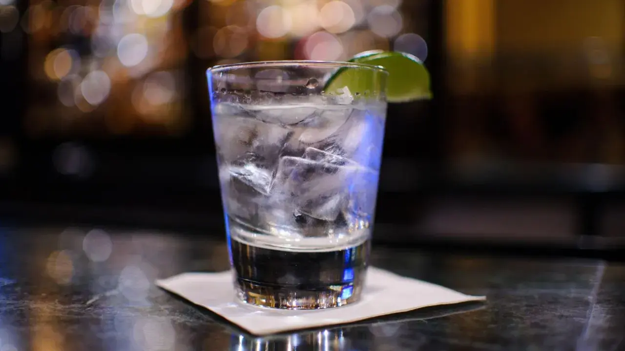 Ein erfrischender Gin Tonic mit Eis und Limette auf einer Bar.