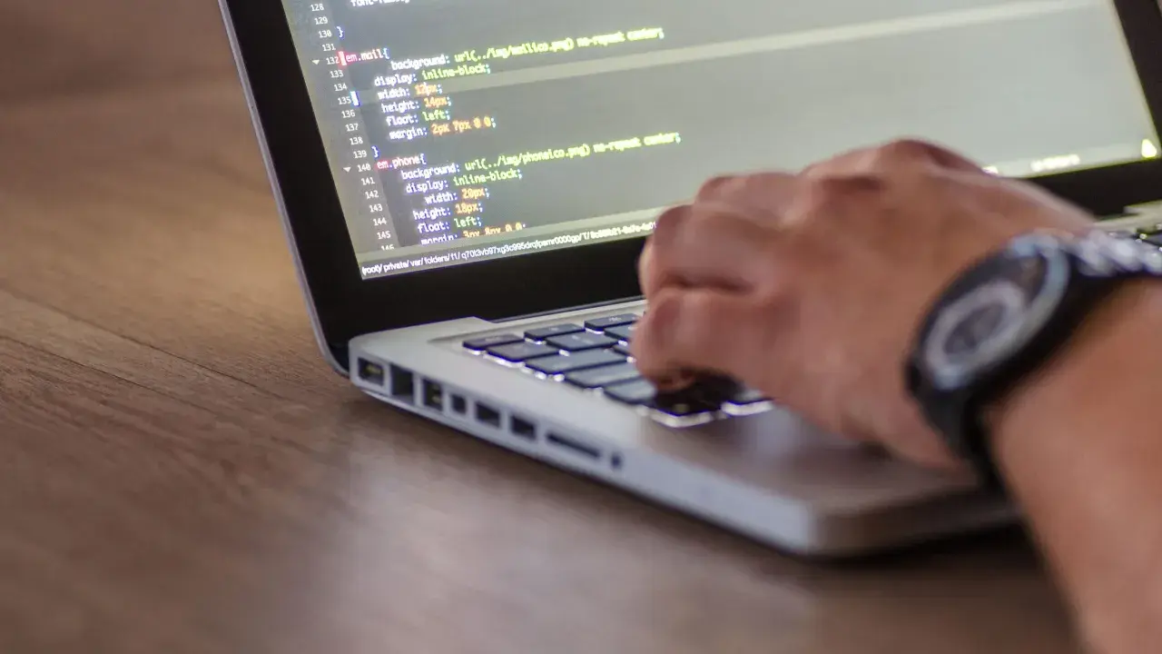 Dłoń pisze kod CSS, optymalizując pliki do wersji min.