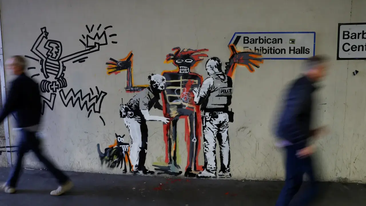 Famous graffiti depicts two police officers interacting with a skeletal figure, with a Keith Haring-esque character and a dog nearby.