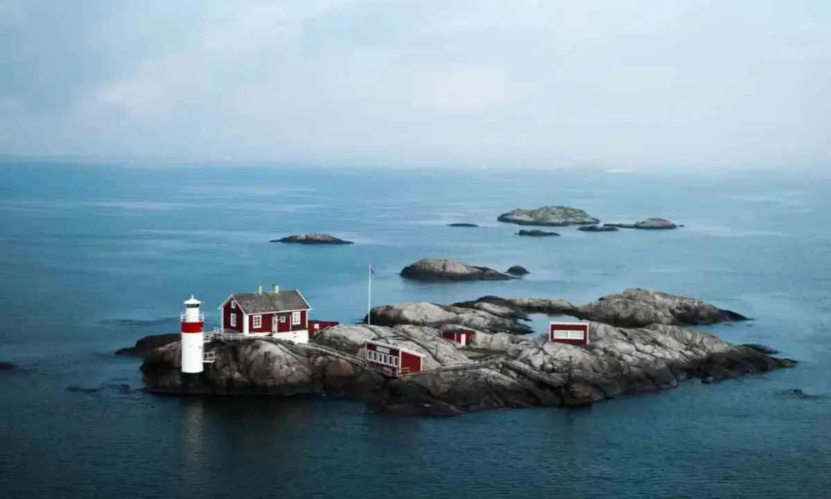 Fyren och röda hus på en klippö bland svenska öar.