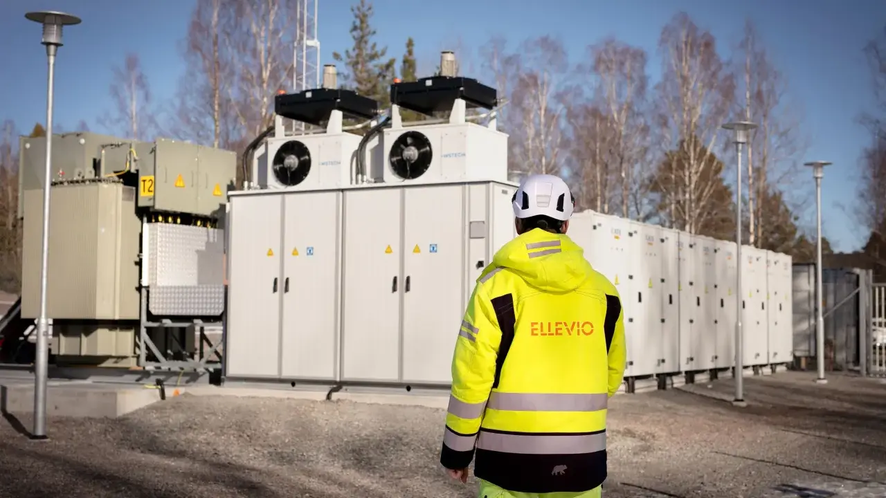 En person i gul jacka står framför en stor fristående batterilagring.