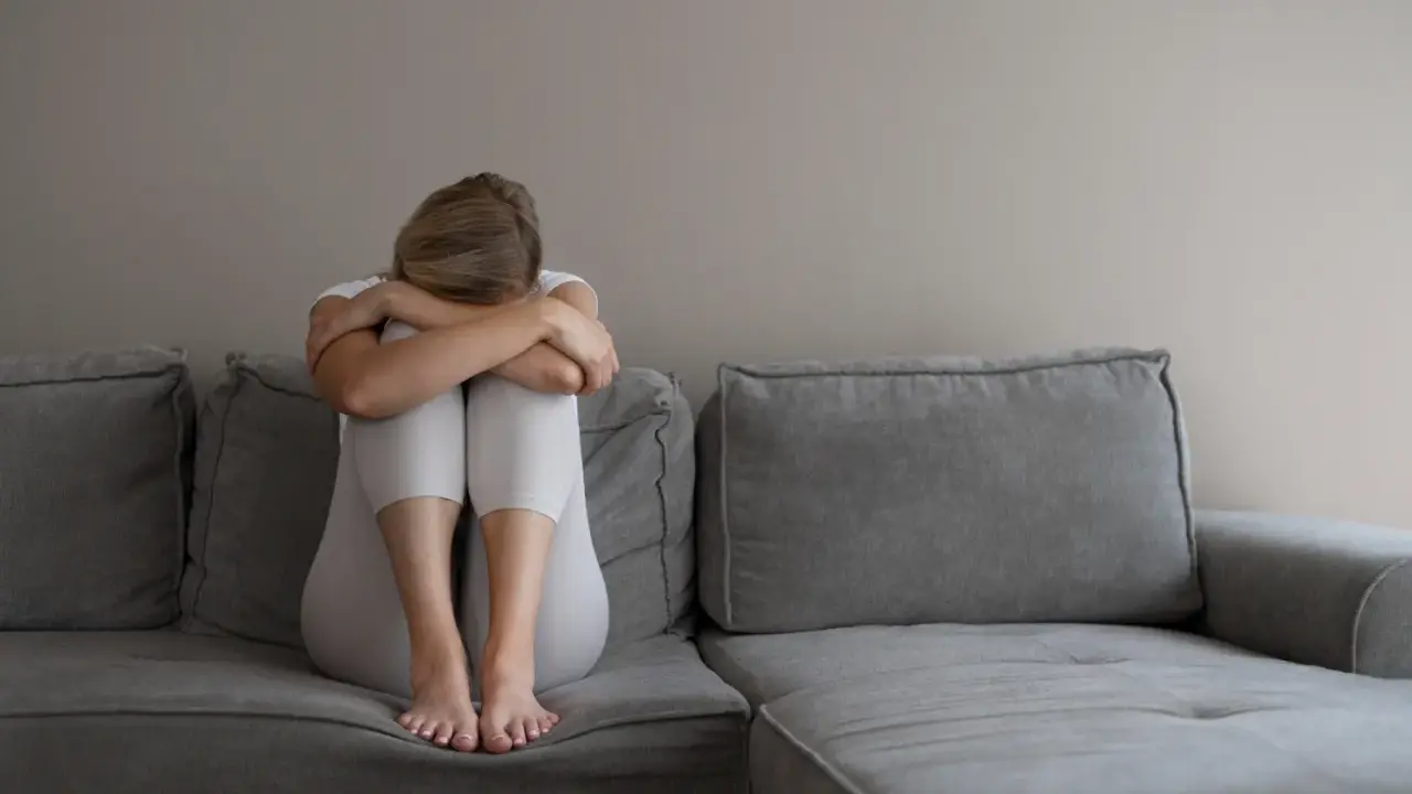 Kobieta z depresją siedzi skulona na kanapie, przygotowując się do komisji lekarskiej ZUS. Co mówić, by uzyskać pomoc?