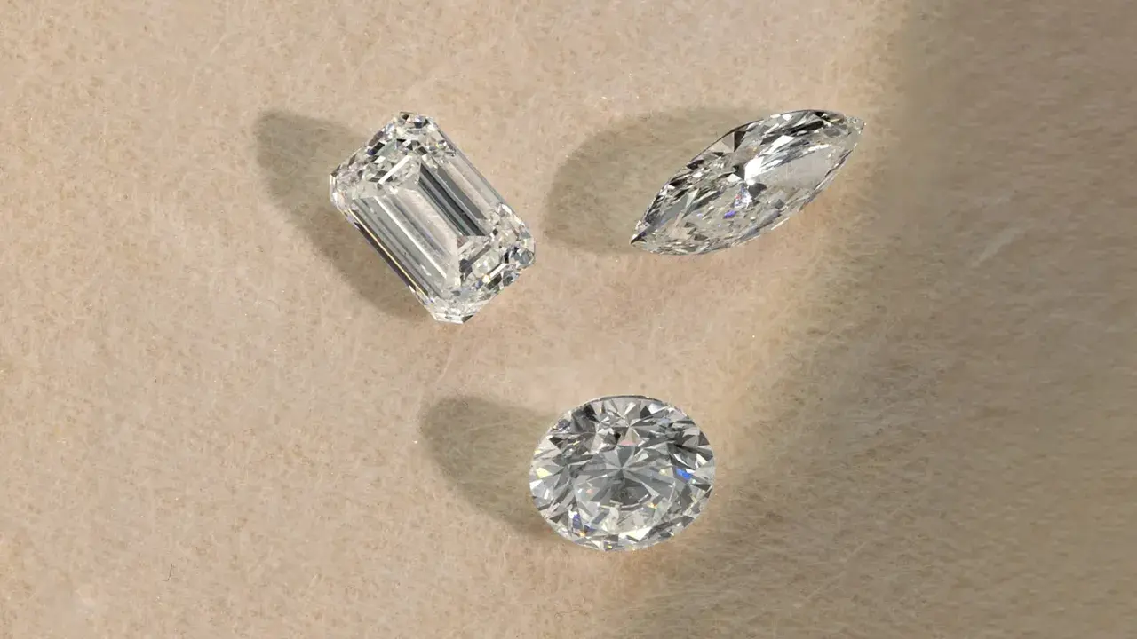 Tre diamanti di taglio diverso (smeraldo, marquise, rotondo) su sfondo chiaro, pronti per la classificazione diamanti.