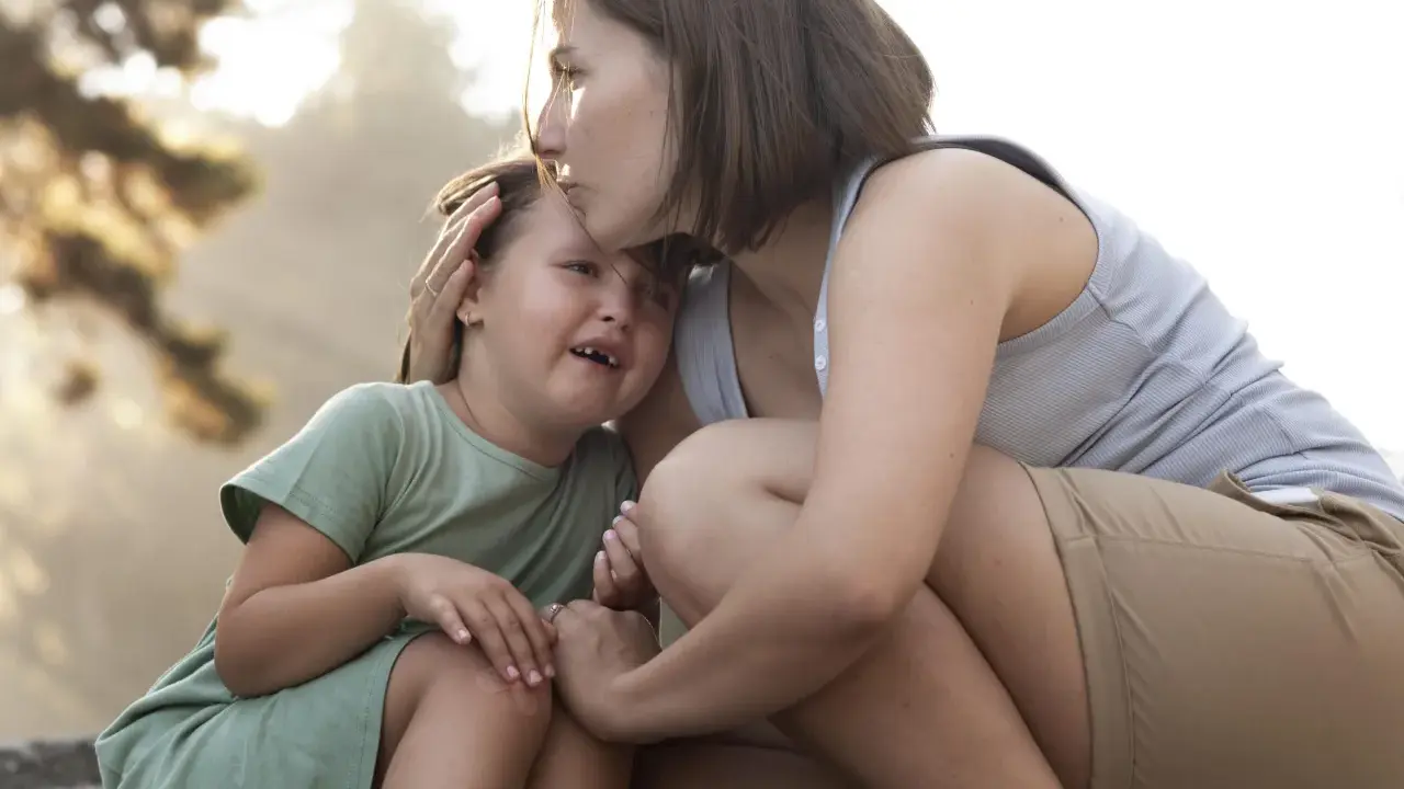 Madre consola la figlia che piange, un abbraccio che mostra le diverse tipologie di attaccamento sicuro e amorevole.