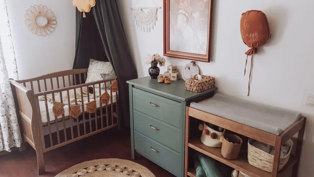 Przytulny pokój dziecka boho z drewnianym łóżeczkiem, przewijakiem i zieloną komodą. Dekoracje w stylu boho tworzą ciepłą atmosferę.