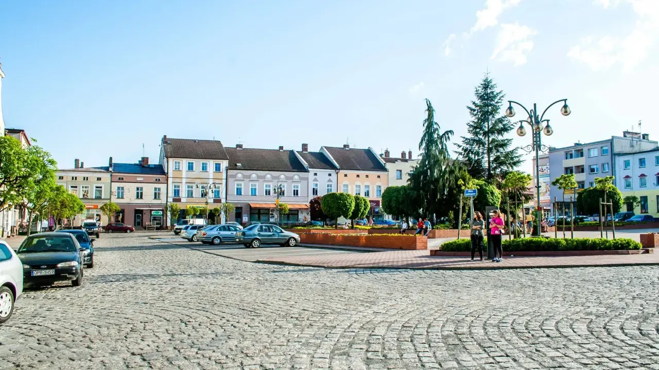Rynek w Krapkowicach z kolorowymi kamienicami i brukowaną nawierzchnią. Atrakcje miasta widoczne w tle.