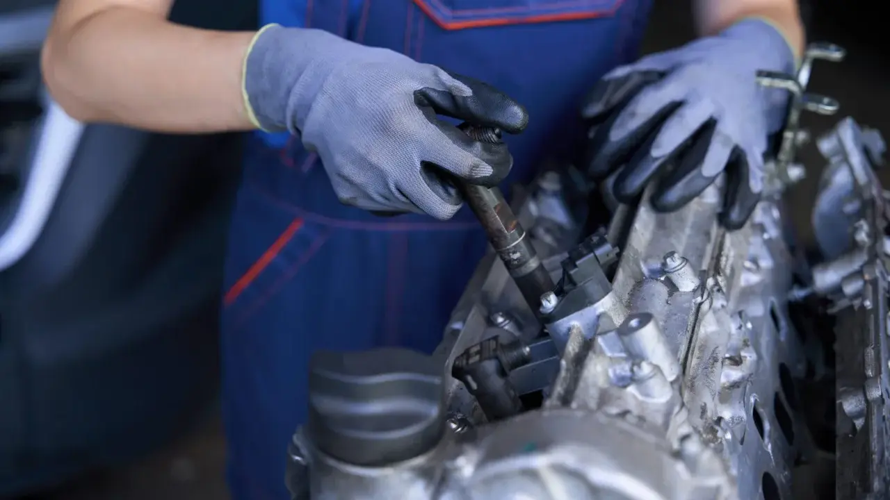 Mecánico con guantes trabajando en un motor, mostrando componentes como inyectores y partes del cigüeñal.