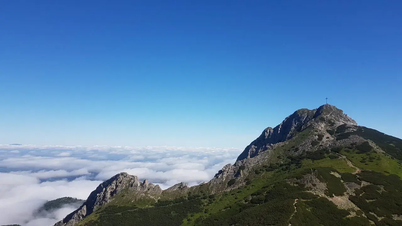 Giewont wysokość 1894 m n.p.m. widoczna z grani, morze chmur poniżej, błękitne niebo.