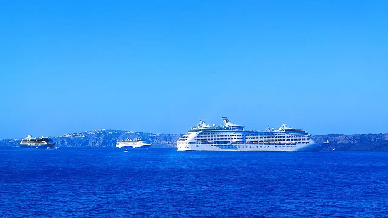Grandi navi da crociera Royal Caribbean navigano in acque blu, con isole sullo sfondo.