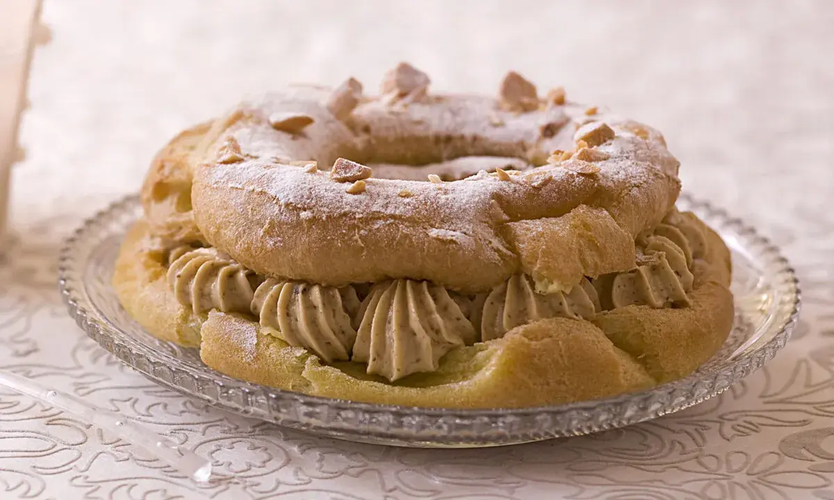 Un Paris-Brest rond, saupoudré de sucre glace et d'amandes effilées, garni d'une généreuse crème diplomate.