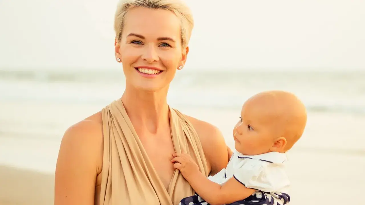 Uśmiechnięta mama z dzieckiem na plaży. Czas na nowe etapy, nawet jeśli to nagłe odstawienie od karmienia piersią.