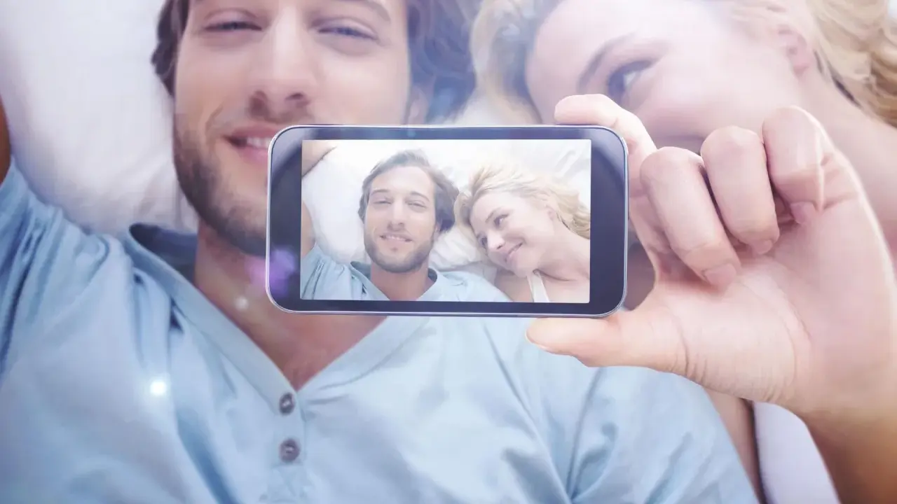 Para widzi na ekranie telefonu siebie, uśmiechnięci i blisko. To piękne objawy zauroczenia.