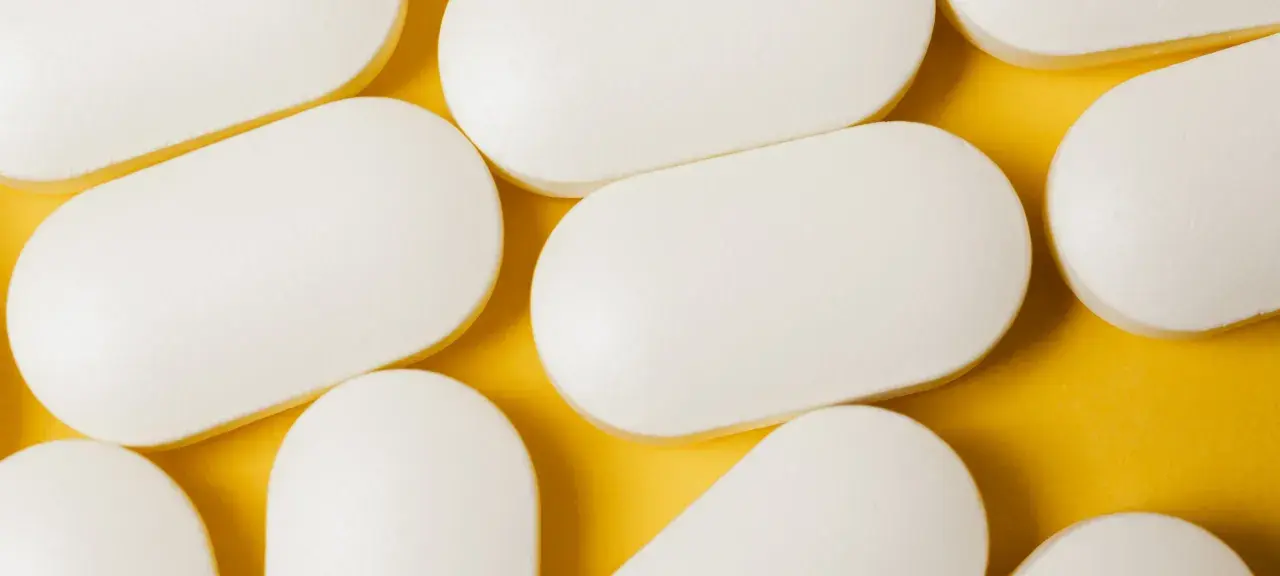 Bianche compresse ovali, disposte su sfondo giallo. Potrebbero essere un antibiotico azitromicina, utili per combattere infezioni batteriche.