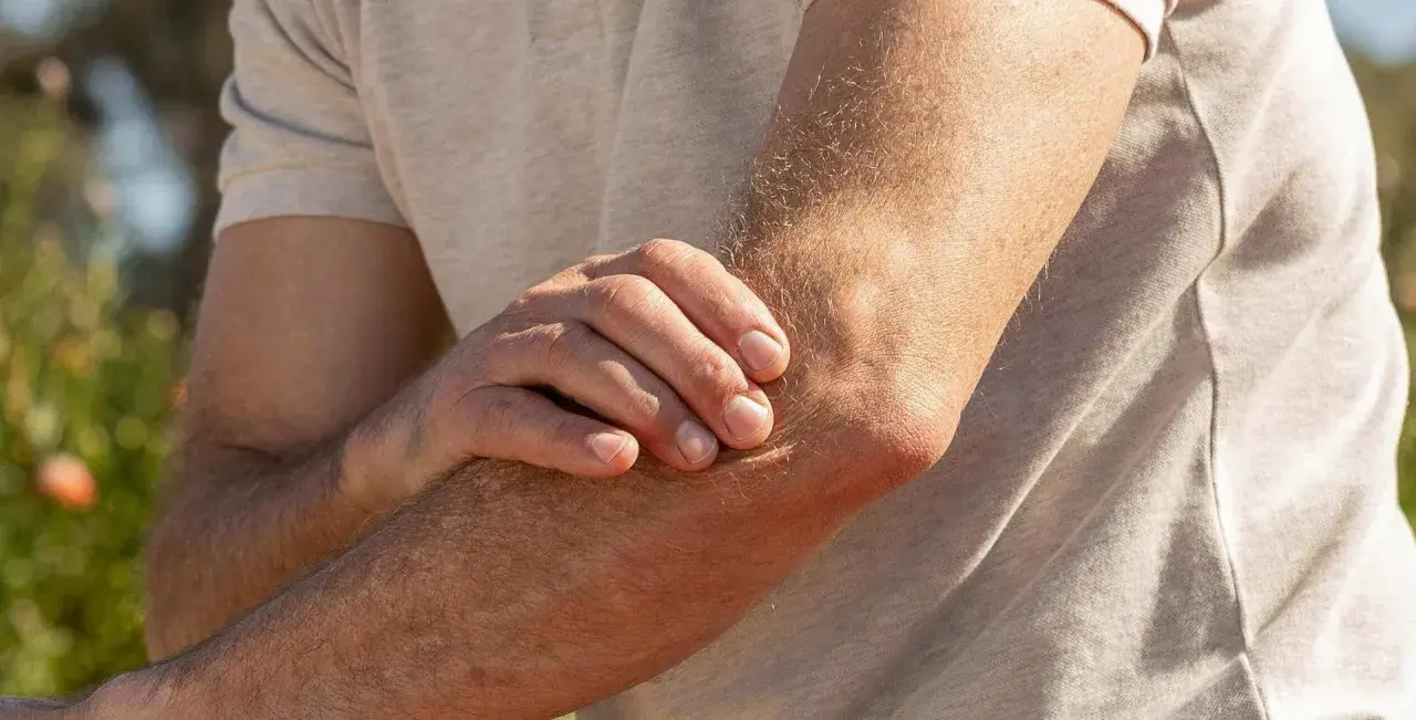 Mann hält seinen Arm, da er Ellenbogen Schmerzen beim Strecken hat.