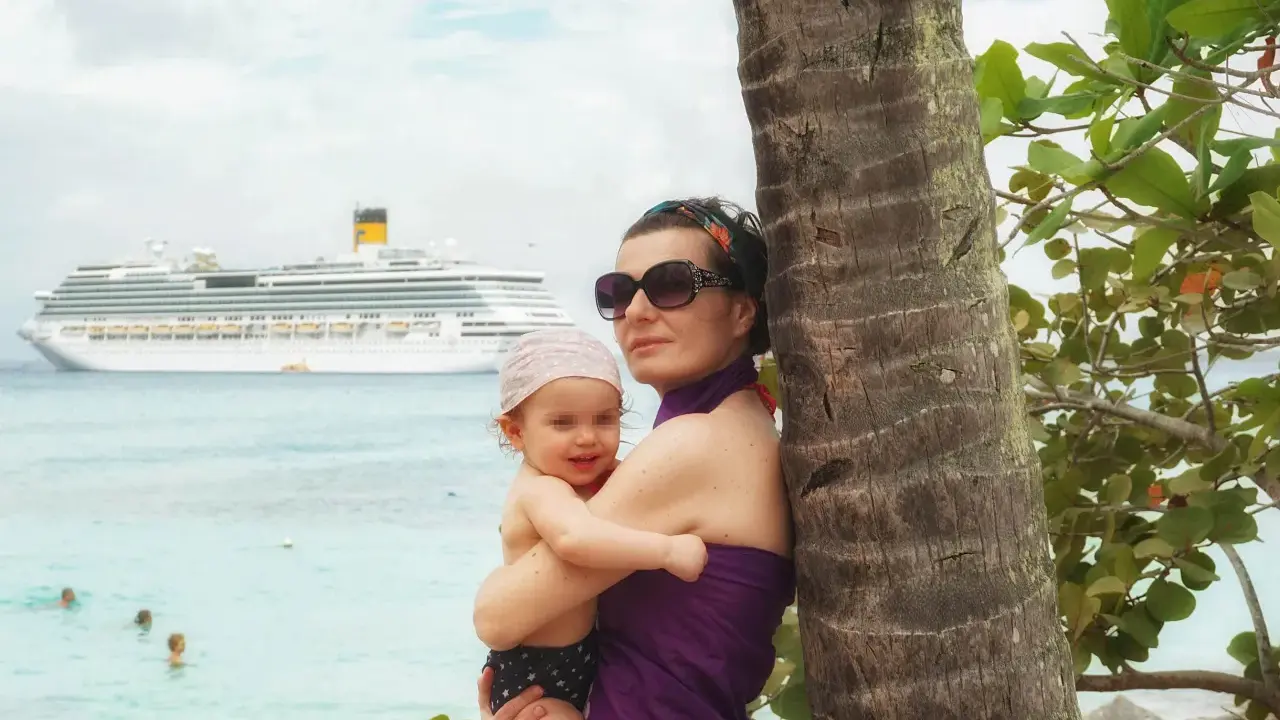 Mamma e bimbo abbracciati vicino a una palma, con una nave da crociera all'orizzonte. Una splendida posizione costa pacifica.