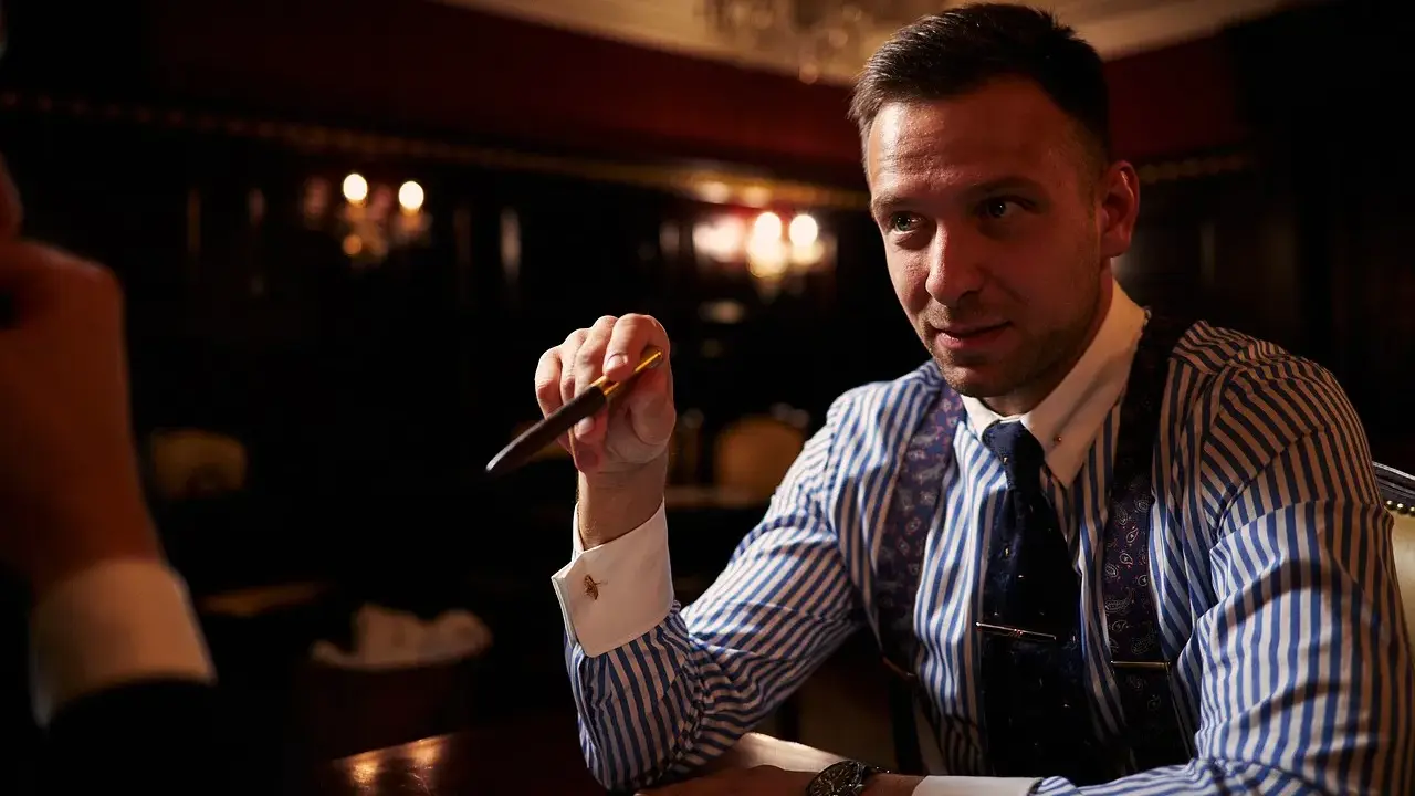 Mężczyzna w eleganckiej koszuli i krawacie trzyma pióro, zastanawiając się, ile bierze adwokat za reprezentowanie w sądzie.